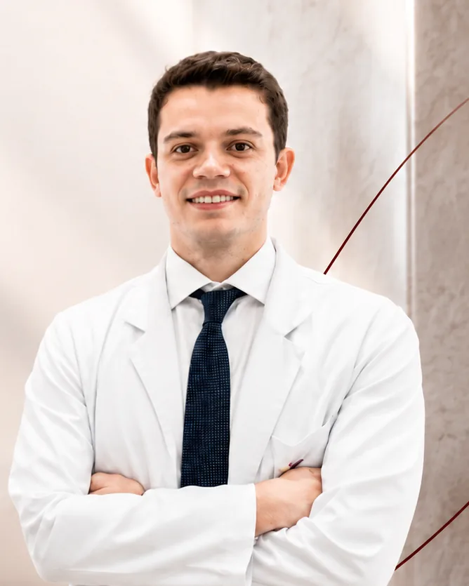 Dr. Eddio Guimarães, cardiologista em Maringá, de jaleco branco e gravata azul-marinho, sorrindo